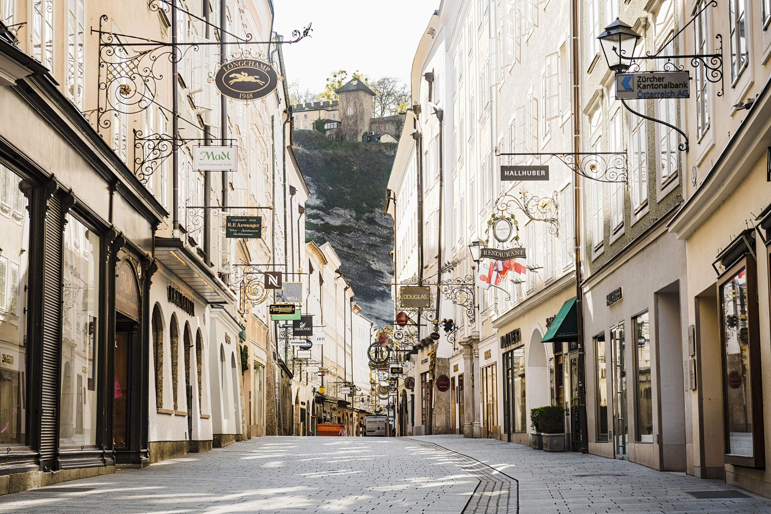 Getreidegasse in Salzburg mit zahlreichen Geschäften und traditionellen Zunftzeichen an den Häuserfassaden.