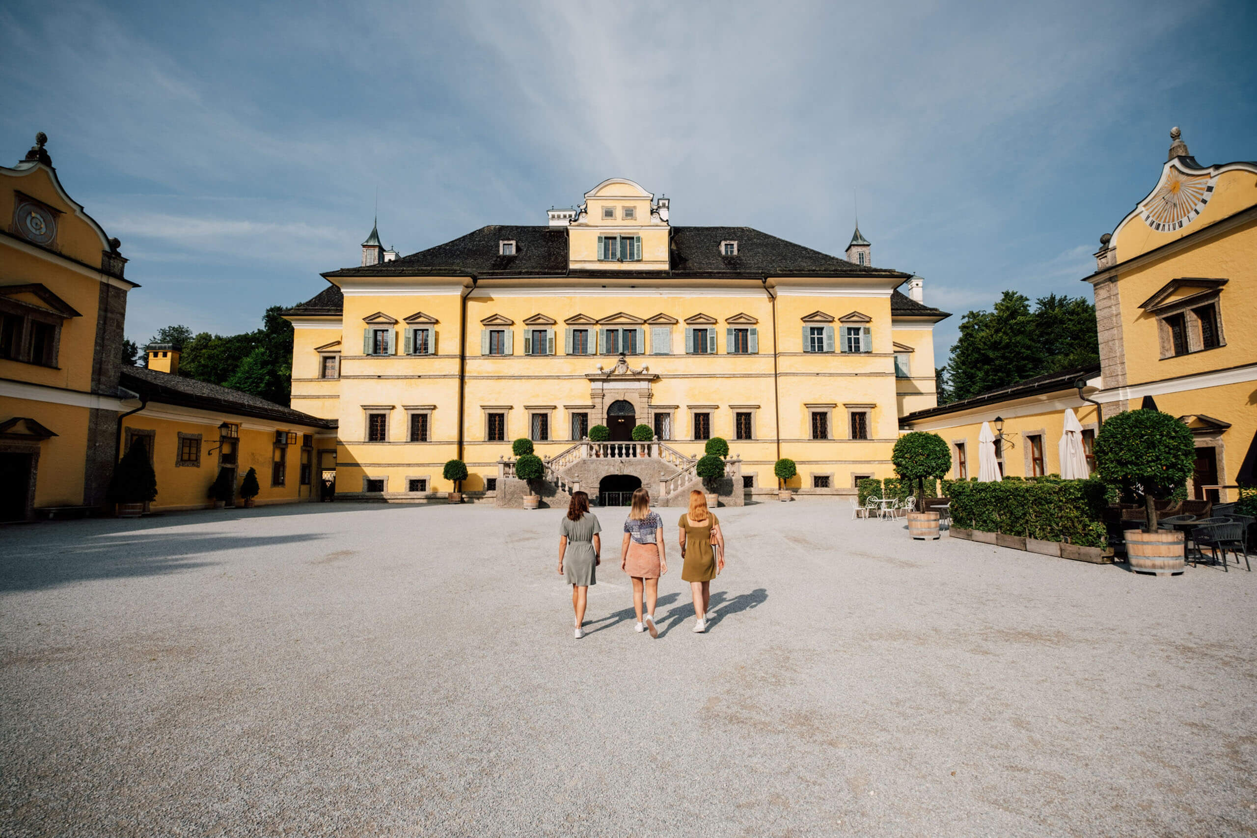 Glückliche Familie vor dem Schloss Hellbrunn in Salzburg bei sonnigem Wetter.