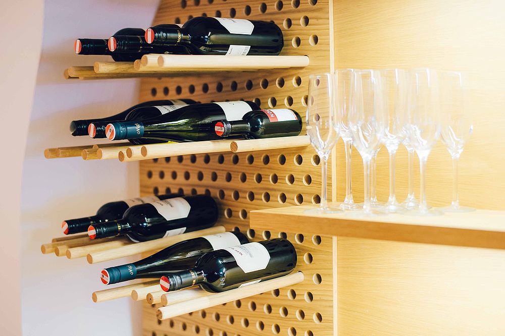 A wooden wine rack on the wall with red wine bottles and champagne glasses in the hotel bar