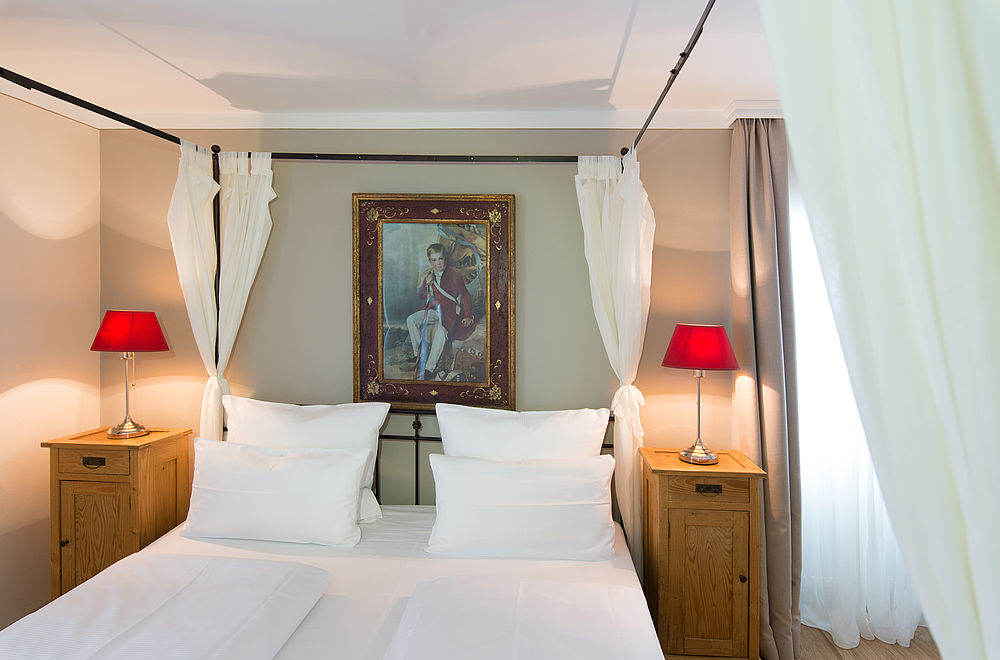 Doppelzimmer mit Himmelbett, Bild und Tischlampen im Hotel Amadeus in der Stadt Salzburg