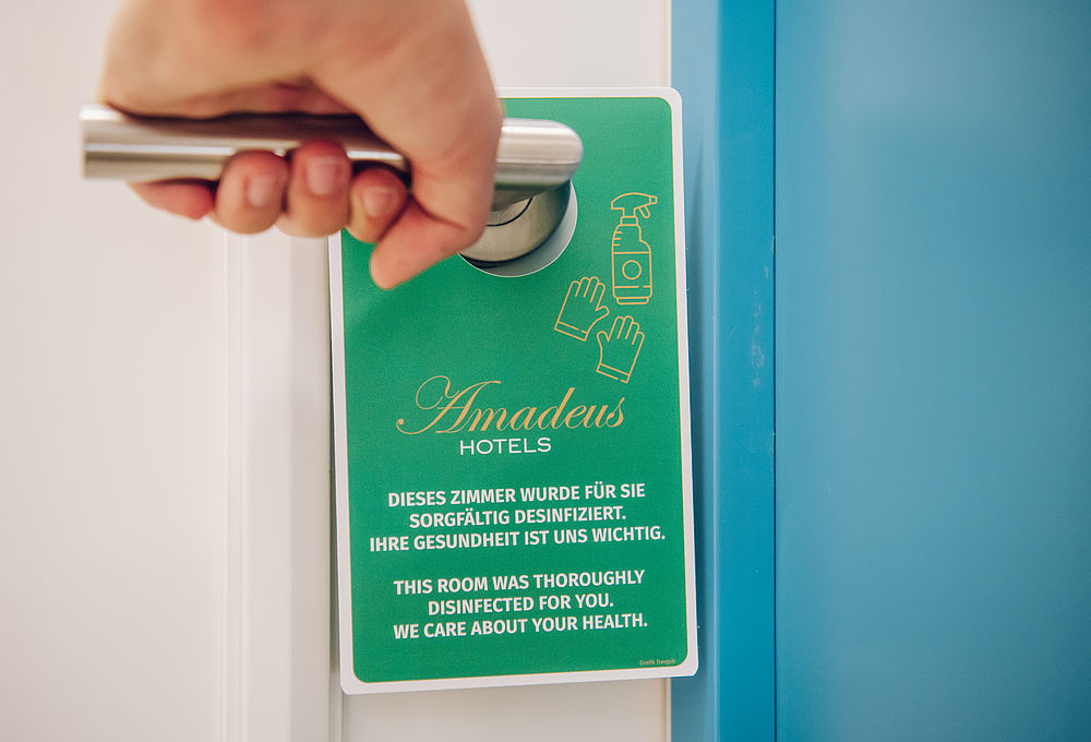 Desinfektionshänger an der Tür eines Hotelzimmers, die gerade geöffnet wird