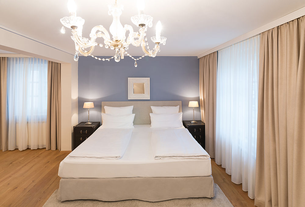 Cosy double room with bed, picture and desk lamps at the Hotel Amadeus in the city of Salzburg