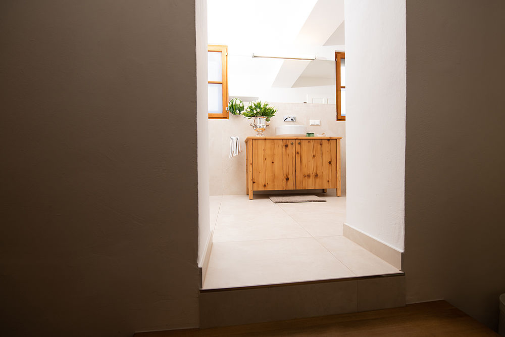 Blick auf das helle Badezimmer mit Holzmöbeln und schickem Waschbecken 