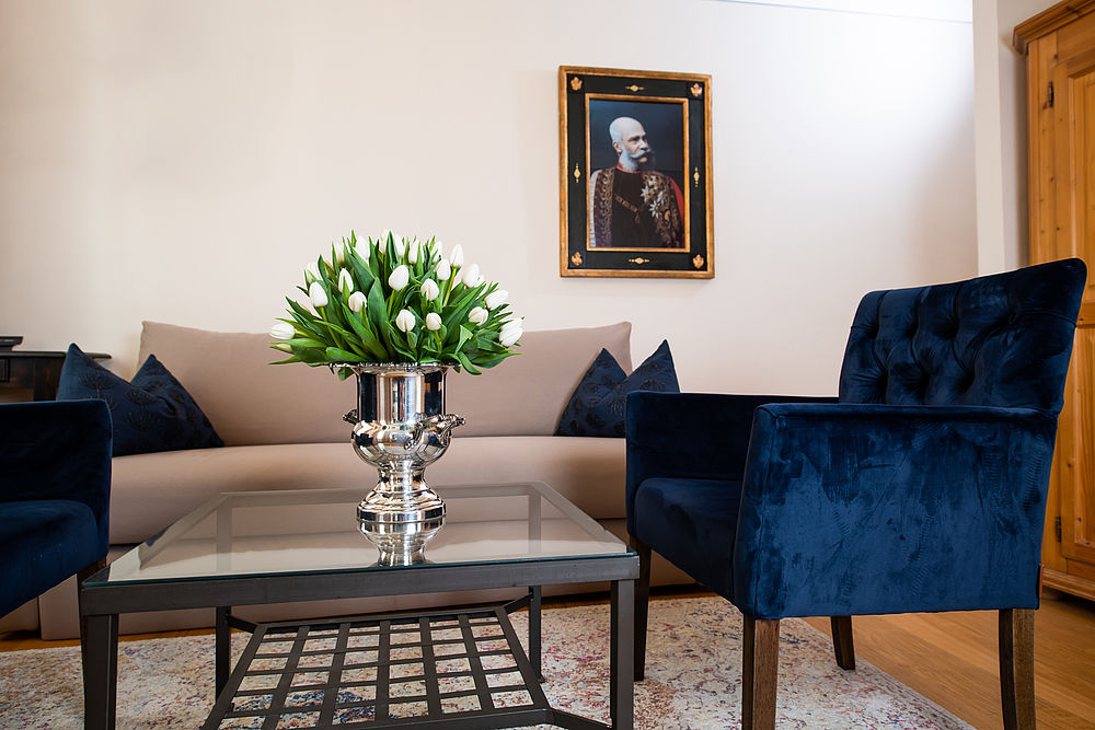 legantes Gästezimmer mit beigem Sofa und blauen Stühlen in Salzburg 