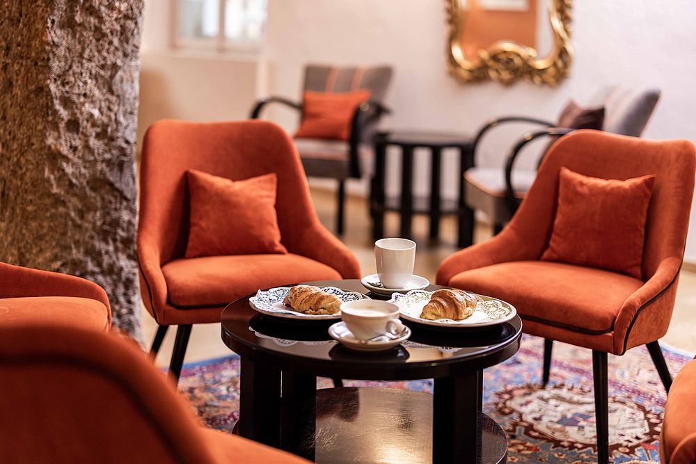 A French breakfast with a croissant and coffee on the table in the cozy hotel lounge