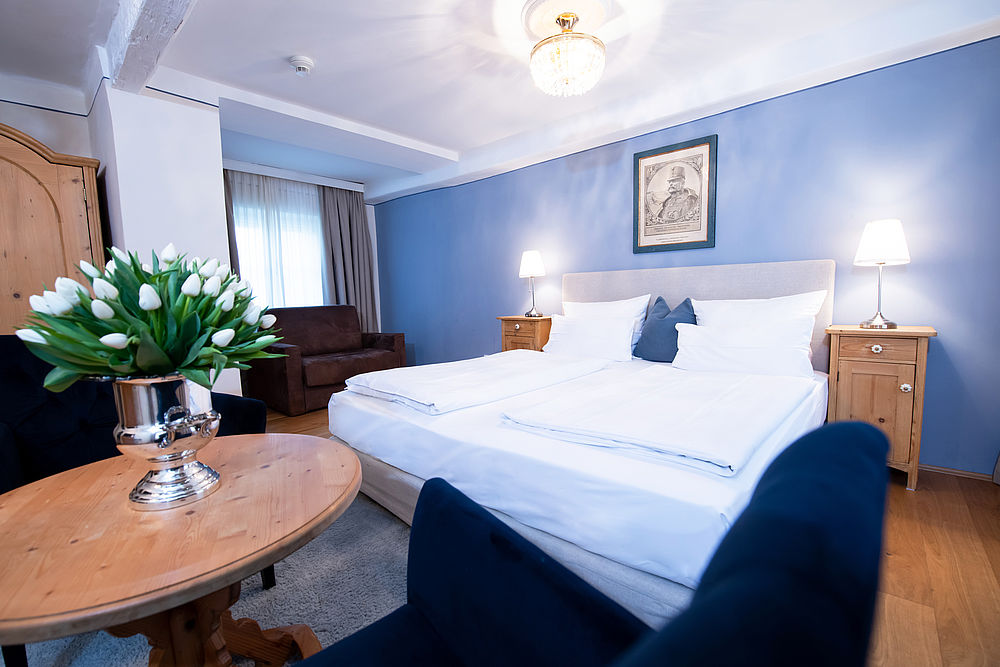 Aufnahme des Wohnbereichs und des Betts im blauen Apartements des Familienhotels Amadeus
