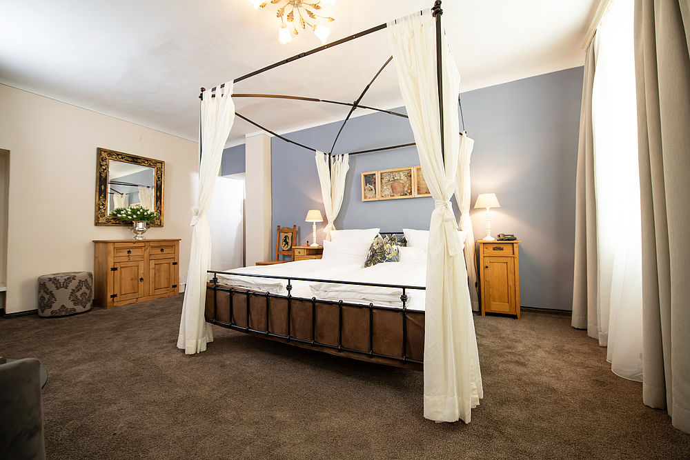 The bedroom of the Junior Suite with a four-poster bed and country-style furniture